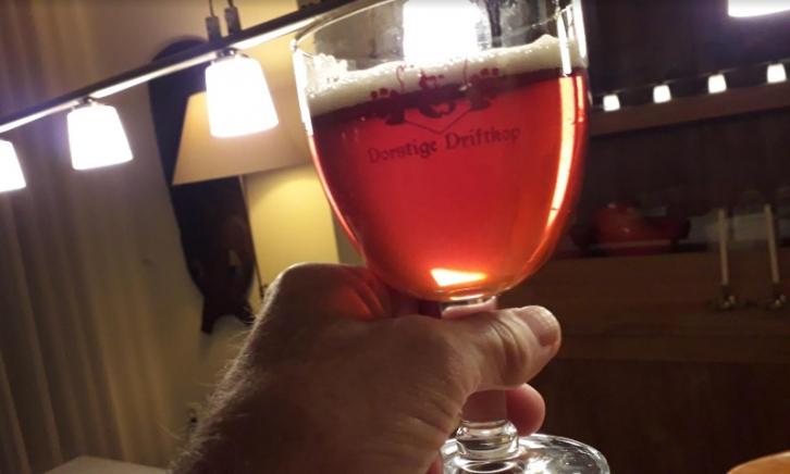 Abdis bier glas in de hand met een tafellamp op de achtergrond